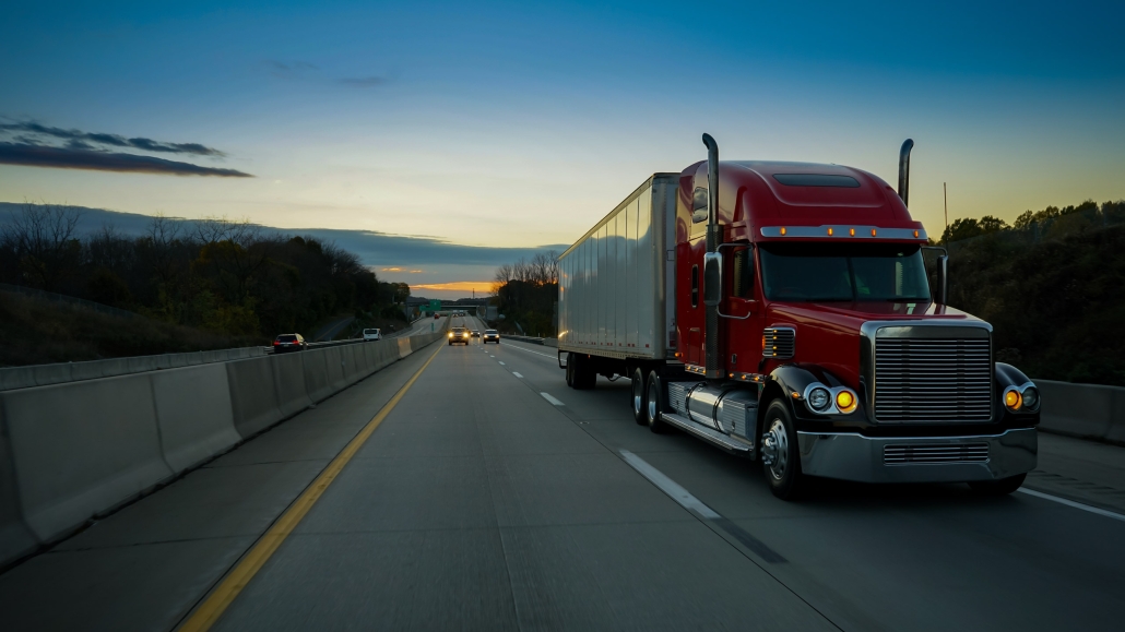 sunset front side view of semi truck driving on highway with light traffic